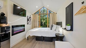 A bedroom with a large bed, a TV mounted on the wall, a water dispenser, and a window with curtains.