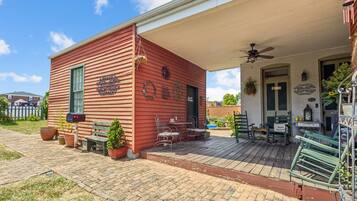 A red building with a porch, outdoor seating, and a mailbox.