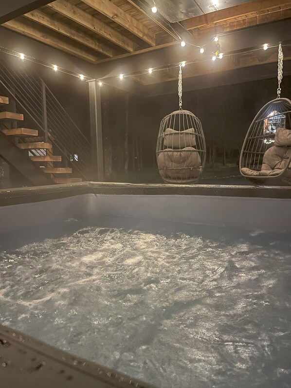 A hot tub area with hanging egg chairs and a wooden staircase.
