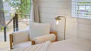 Un dormitorio acogedor con una cama de madera, un almohadón blanco y una lámpara de noche.