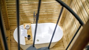 Una cabaña de madera con una bañera blanca, una toalla y un libro.