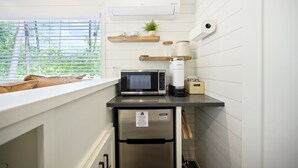 A compact kitchen with a microwave, coffee maker, and a small refrigerator.