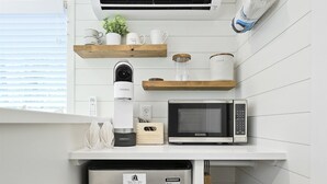 A compact kitchen with a stainless steel refrigerator, a microwave, and a Keurig coffee maker on a white countertop.