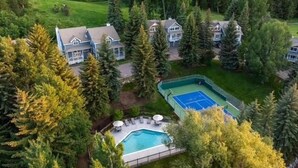 A residential area with multiple houses surrounded by dense forest, a swimming pool, and a tennis court. - 405 Greenway Circle 4 Bedroom Home by RedAwning (Avon)
