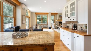 A spacious kitchen with a granite island, white cabinetry, and large windows offering views of the outdoors. - 405 Greenway Circle 4 Bedroom Home by RedAwning (Avon)