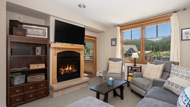 A cozy living room with a fireplace, comfortable seating, and a large window offering a scenic view. - Value Unit 1422 - 2br - Zephyr Mountain Lodge 2 Bedroom Condo (Winter Park)