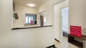 A hallway with a black countertop, a red informational sign, and a glimpse of a bedroom with a bed. - XXV Aprile Downtown by Wonderful Italy (Genoa)