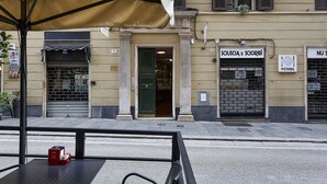 A street view with a building featuring a pizzeria sign and a closed shuttered shop. - XXV Aprile Downtown by Wonderful Italy (Genoa)