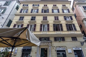 A multi-story building with a classic architectural style, featuring a ground-level shop with signage for a pizza restaurant and a bookstore. - XXV Aprile Downtown by Wonderful Italy (Genoa)