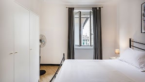 A hotel room with a bed, a wardrobe, a window with curtains, and a nightstand with a lamp. - XXV Aprile Downtown by Wonderful Italy (Genoa)