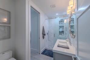 A modern bathroom with a glass shower enclosure, a white sink with a mirror, and a towel rack. - Naples Park Retreat w/ Heated Pool, Sleeps 8 (Naples)