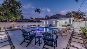 Ein Garten mit Schwimmbad, Liegestühlen und einer Terrasse.