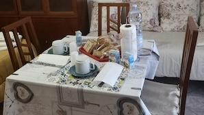 A dining table with a clock-themed tablecloth, a basket of bread, a water bottle, and a tissue roll. - Antico Portale Host Roberto (Regalbuto)