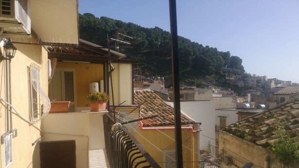 A balcony with a view of a hillside and neighboring buildings. - Antico Portale Host Roberto (Regalbuto)