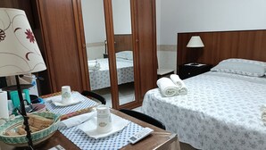 A hotel room with a bed, a desk with a lamp, a mirror, and a bathroom visible through an open door. - Antico Portale Host Roberto (Regalbuto)