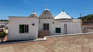 A building with three distinct roofs, a small entrance, and a paved ground. - 4072 Trull' Itria by Barbarhouse (Martina Franca)