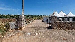 A paved pathway leading to a gated area with stone walls and white-roofed buildings. - 4072 Trull' Itria by Barbarhouse (Martina Franca)