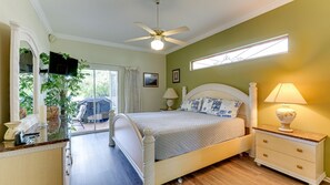 A bedroom with a bed, a nightstand, a lamp, a ceiling fan, a window, and a view of the outdoors. - Home Near Downtown Bradenton (Bradenton)
