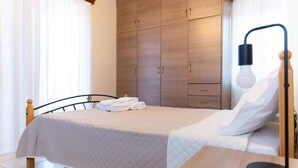 Una cama bien hecha con colcha acolchada, una mesita de noche con lámpara y un armario con varios compartimentos.