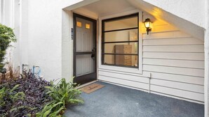 A white building with a dark-framed door and a window with a view of a room inside. - 2 Bed 2 Bath Condo on Golf Course in Quiet Safe Community, 4 Miles to Beach (Venice)
