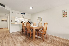 A dining area with a wooden table and chairs, a kitchen in the background, and a mirror on the wall. - 2 Bed 2 Bath Condo on Golf Course in Quiet Safe Community, 4 Miles to Beach (Venice)