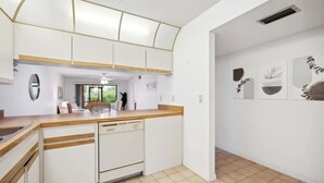 A modern kitchen with white cabinetry, a wooden countertop, and a dishwasher. There is a dining area visible through an open door. - 2 Bed 2 Bath Condo on Golf Course in Quiet Safe Community, 4 Miles to Beach (Venice)