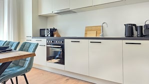 Eine moderne Küche mit weißen Schränken, einer schwarzen Arbeitsplatte und einem Holzespeisetisch mit blauen Stühlen.