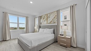 Une chambre d’hôtel moderne avec un grand lit, des tables de chevet et une vue sur la ville.