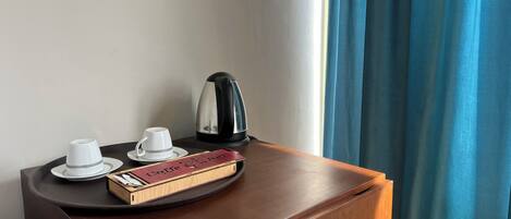 Una mesita de noche de madera con una tetera, dos tazas y una bandeja con un libro.