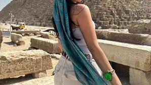 Une personne se tient devant une grande structure pyramidale.
