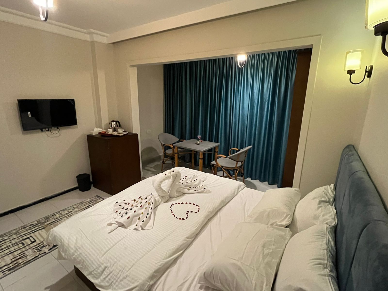 A hotel room with a bed, a desk, a chair, a television, and a curtain.