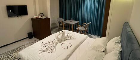 A hotel room with a bed, a desk, a chair, a television, and a curtain.