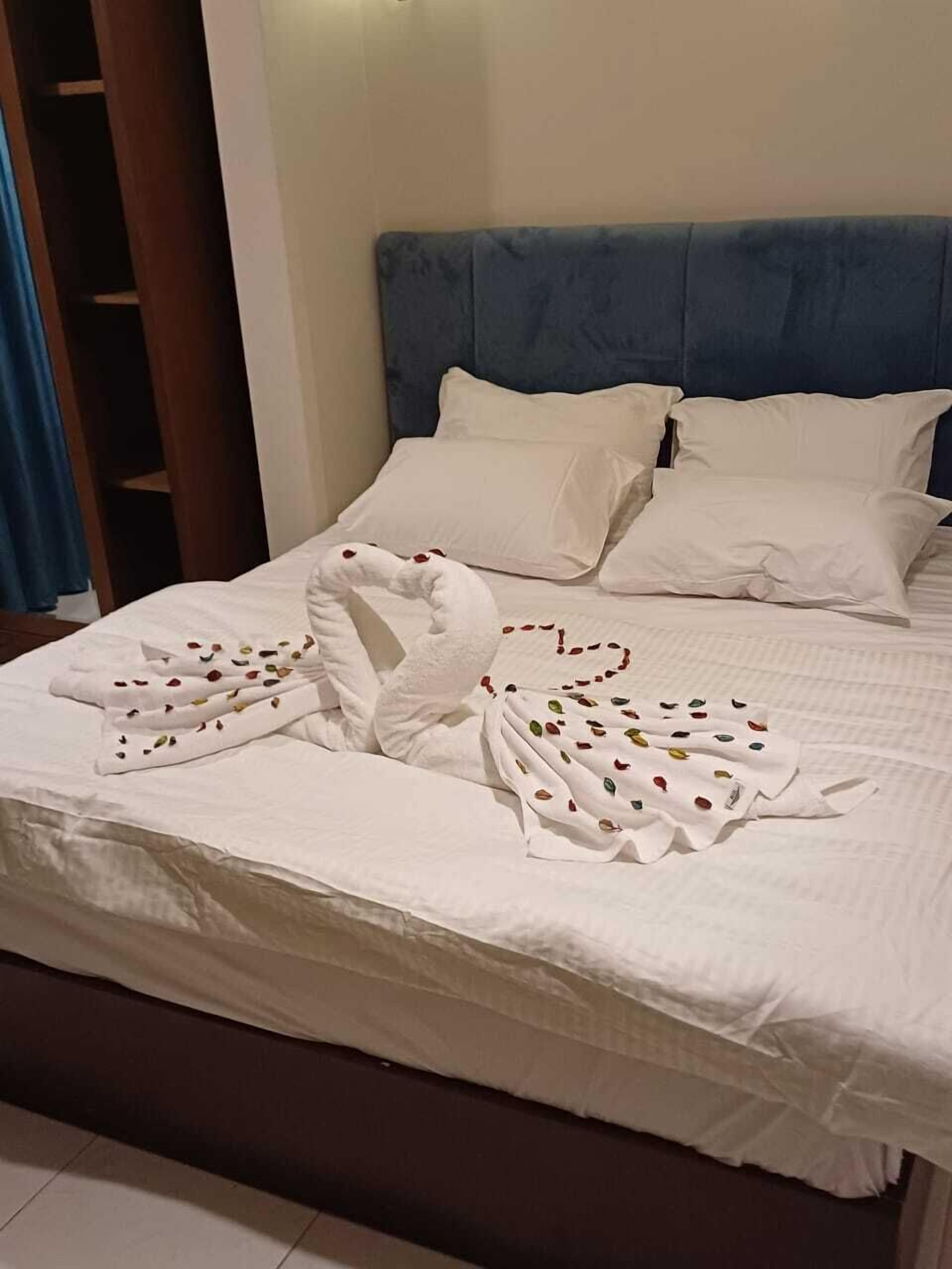 A neatly made bed with white linens and a decorative towel arrangement in the shape of swans.