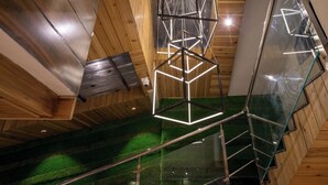 A modern interior with wooden paneling and a glass staircase. - Hotel Finger lime (Gangtok)