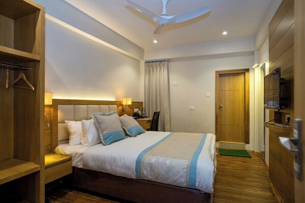 A hotel room with a bed, bedside table, lamp, wardrobe, and a television. - Hotel Finger lime (Gangtok)
