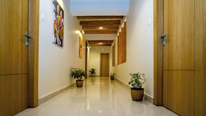 A hallway with wooden doors, potted plants, and a ceiling with exposed beams. - Hotel Finger lime (Gangtok)