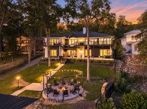 Une maison moderne à deux étages dotée d’un jardin aménagé à l’arrière, comprenant un foyer extérieur et un espace salon extérieur.