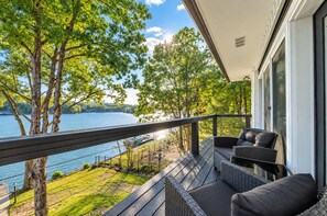 Een balkon met rieten meubilair met uitzicht op een meer.