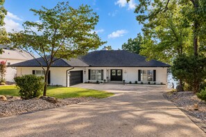 Une maison de plain-pied avec un garage, un porche à l’avant et une allée.