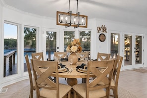 Un coin repas avec une table ronde, des chaises en bois, un vase de fleurs et un lustre.