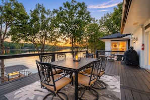 Une terrasse avec une table et des chaises, donnant sur une étendue d’eau et des arbres.