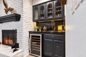 Eine moderne Küche mit Kamin, dunklen Schränken und einer Neonreklame.
