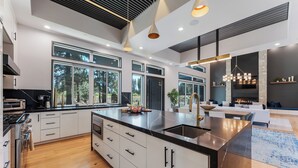 Een moderne keuken met een groot kookeiland, inbouwapparatuur en grote ramen.
