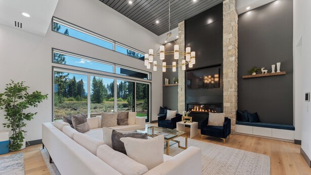 Een moderne woonkamer met een royale hoekbank, een open haard en een groot raam met uitzicht op de omgeving.