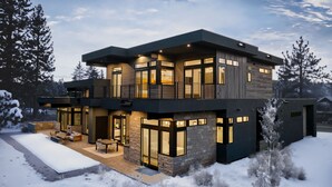 Een modern huis met twee verdiepingen, een stenen gevel, grote ramen en een balkon.