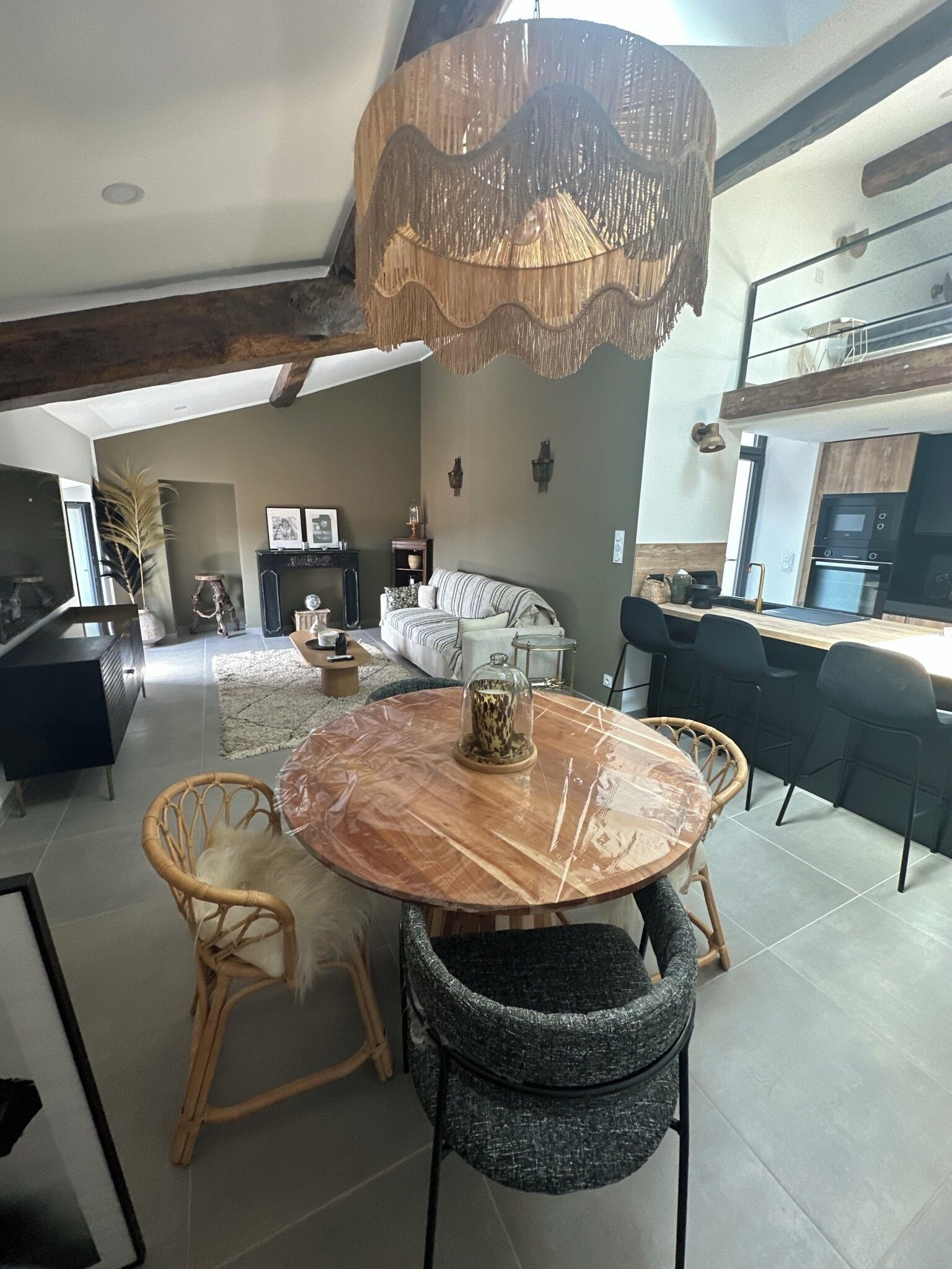 A modern kitchen with a built-in oven and microwave, a dining area with a round table and chairs, and a living room with a sofa and decorative items.