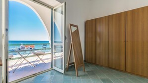 A room with a view of the ocean, a wooden wardrobe, and a small table with chairs.