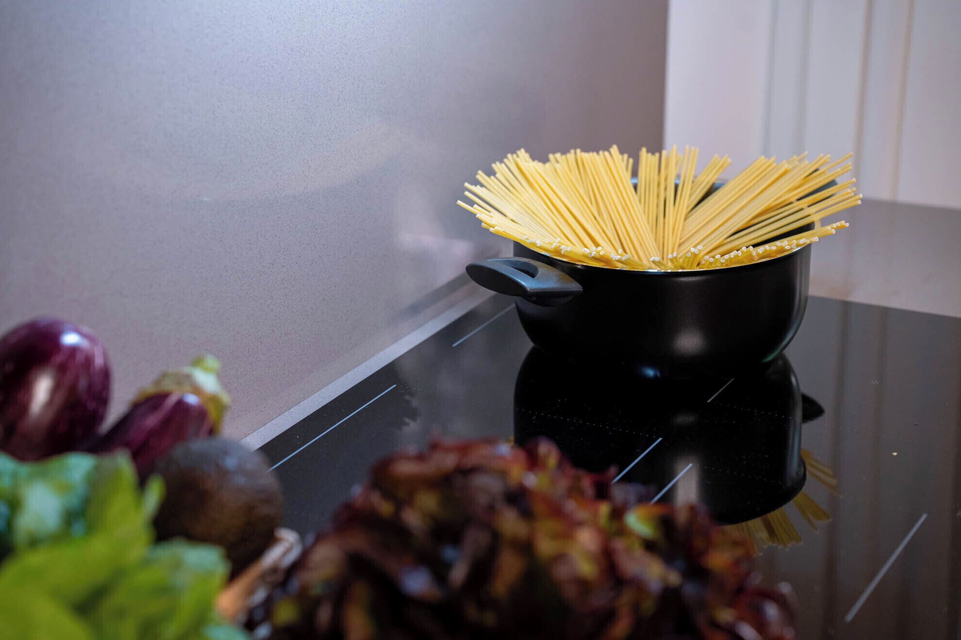 Una olla de espagueti sin cocinar sobre una estufa.