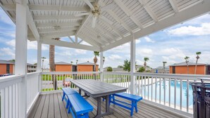 A covered outdoor area with a pool, wooden deck, and blue benches.