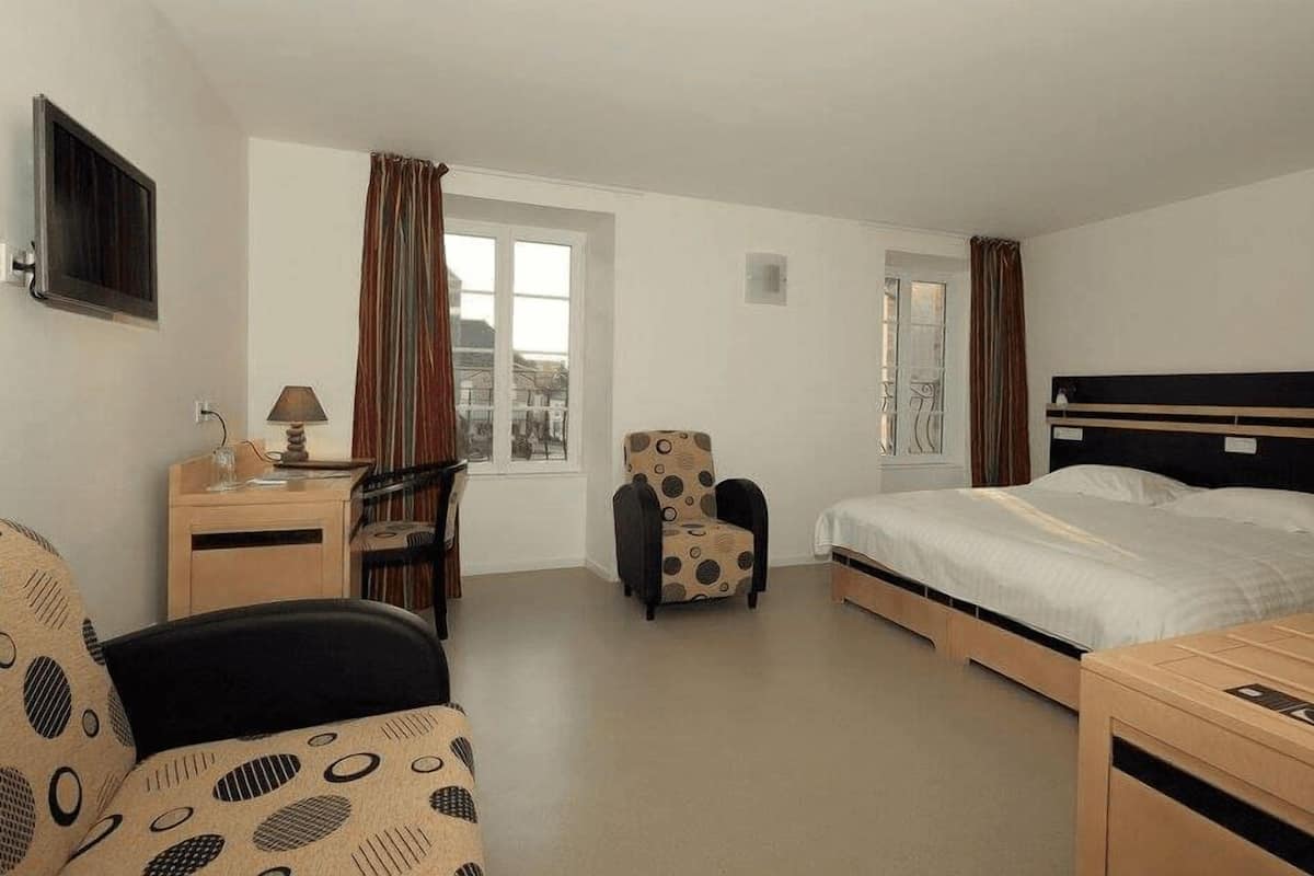 Een hotelkamer met een bed, een bureau, een stoel en een raam.